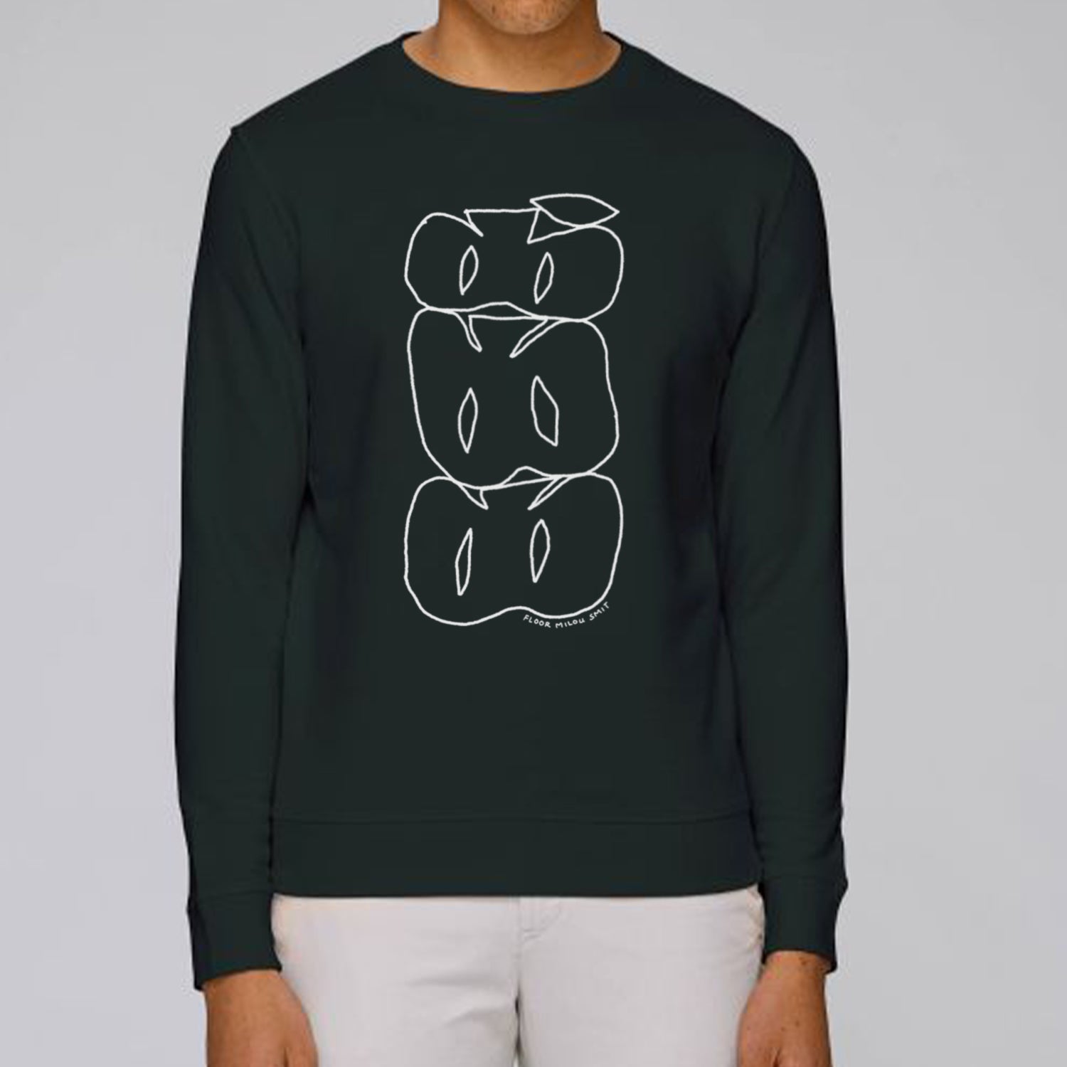 Photo of a model wearing a black sweater. The print on the sweater is a white line art drawing of 3 cut apples on top of each other forming a stack.